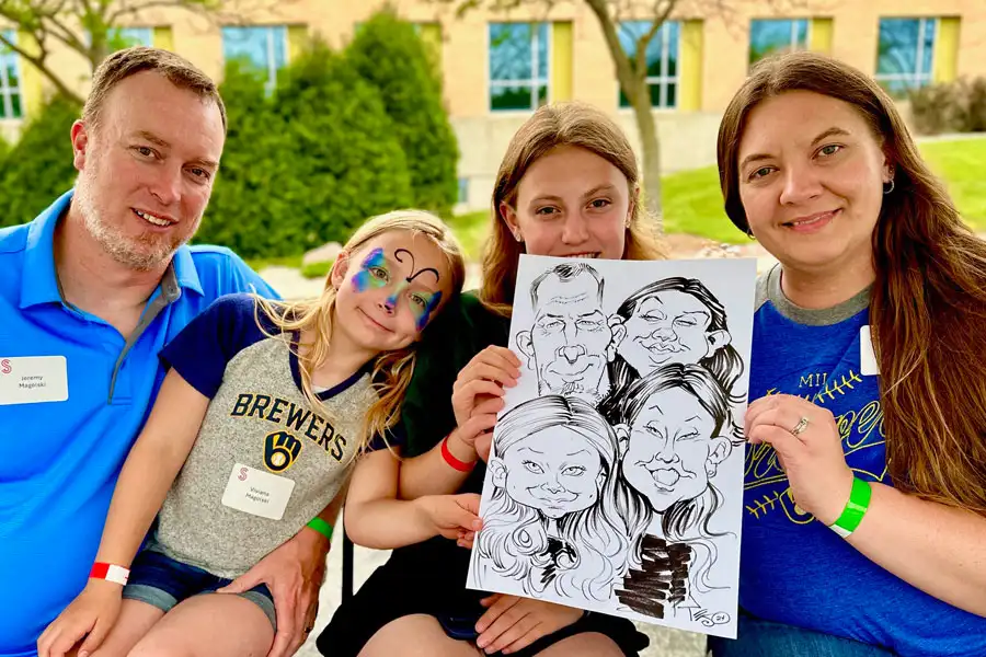 Family Holding Their Caricature At A Company Picnic