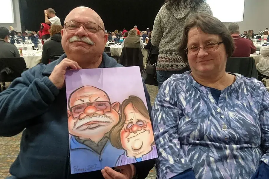 Couple Holding Their Caricature At A Holiday Party